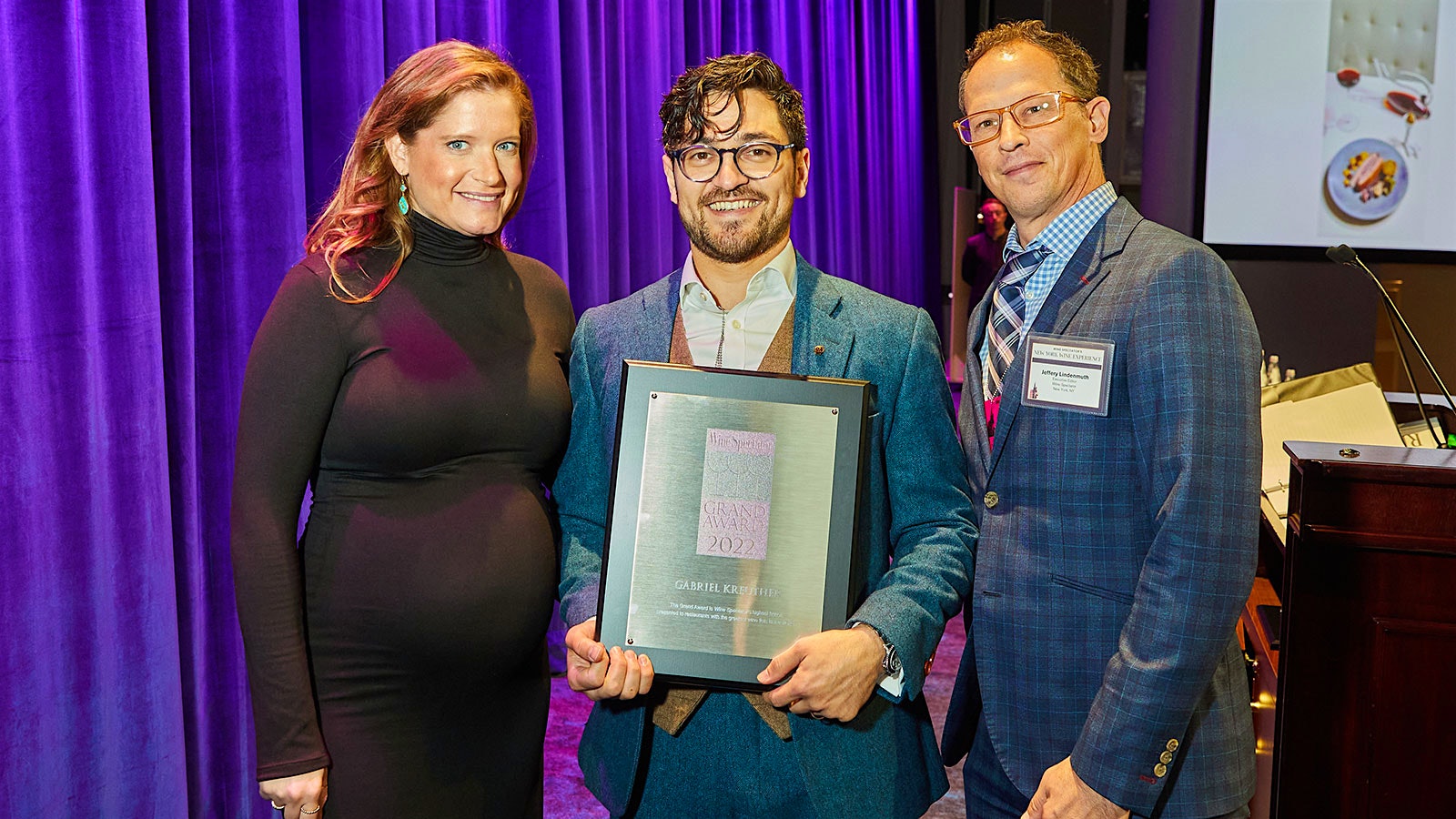 Gabriel Kreuther wine director Aukai Bell (center) accepts the Grand Award plaque from Restaurant Awards director Cassia Schifter (right) and Wine Spectator executive editor Jeffery Lindenmuth (left)